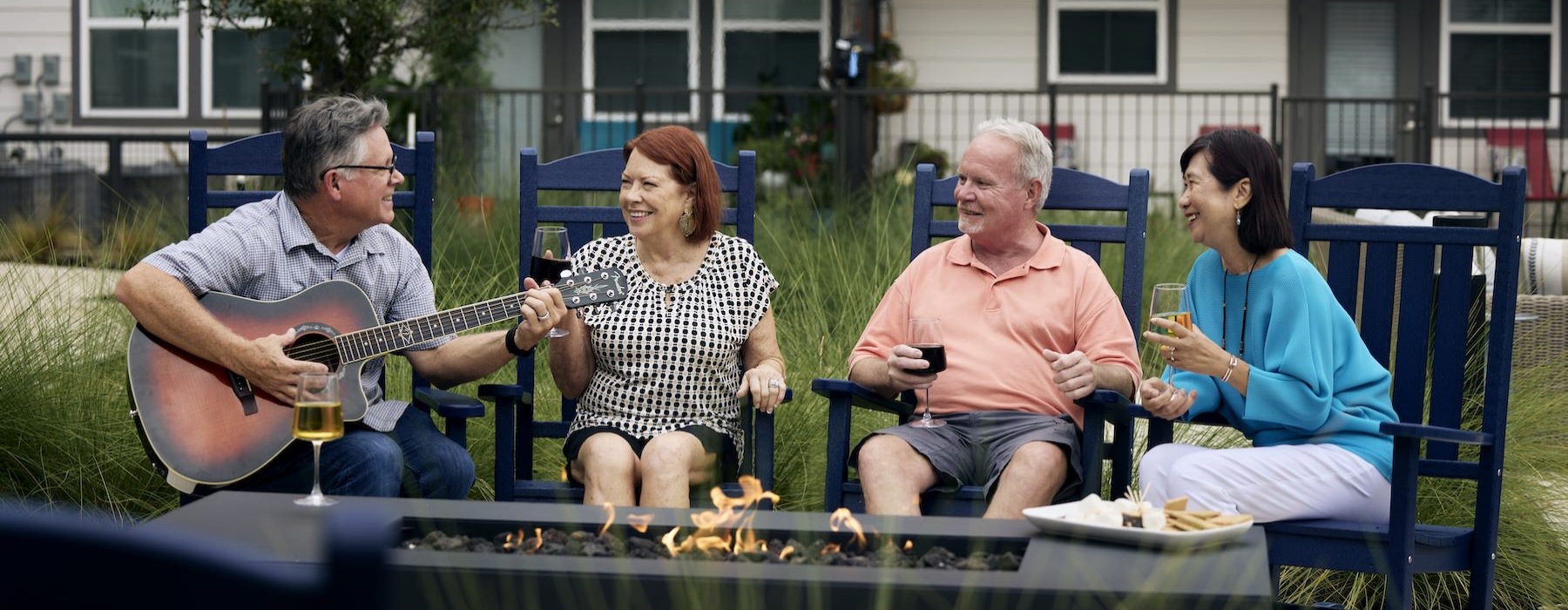 The lifestyle you've been waiting for. people sitting around fire and a man playing a guitar