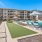 a group of lounge chairs next to a tennis court and a pool